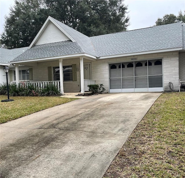 ranch-style house featuring covered porch, a garage, and a front lawn