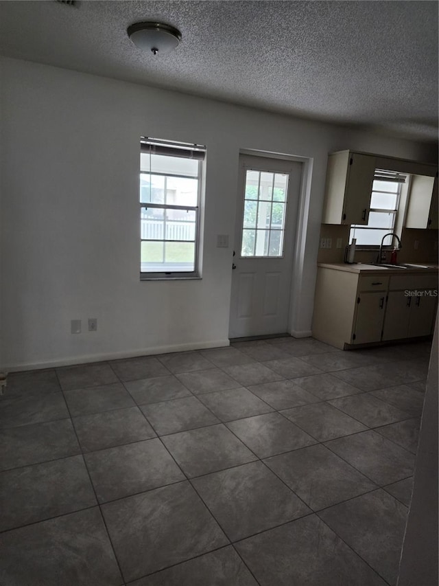 interior space featuring sink, a textured ceiling, and tile patterned flooring