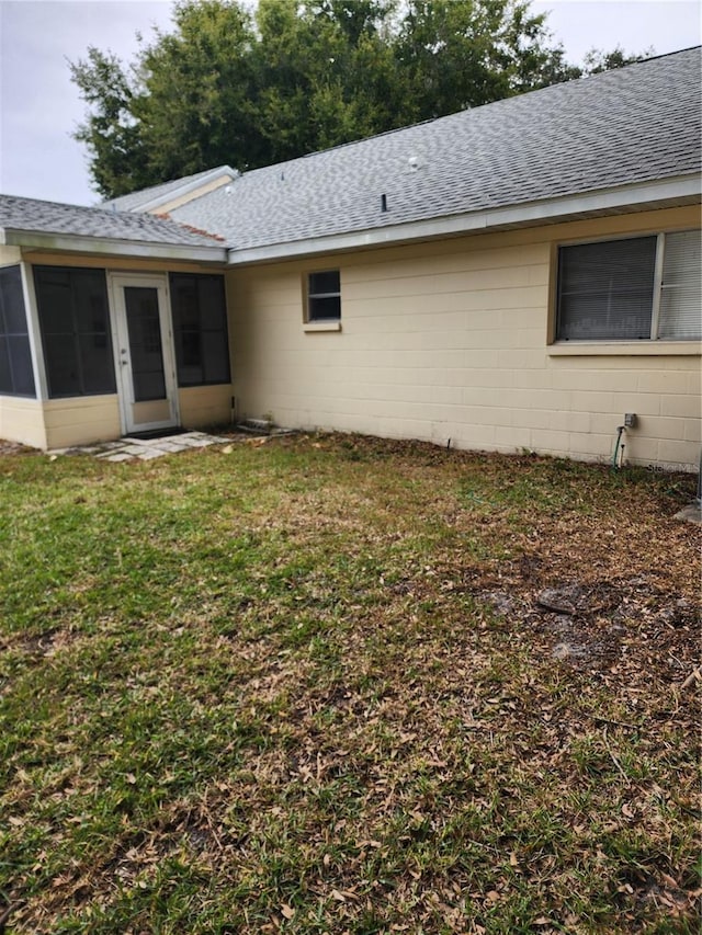 rear view of property featuring a sunroom and a yard