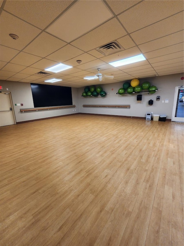 exercise room with a drop ceiling and light hardwood / wood-style flooring