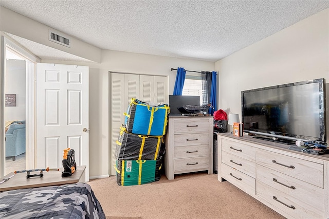 bedroom featuring light colored carpet, a textured ceiling, and a closet