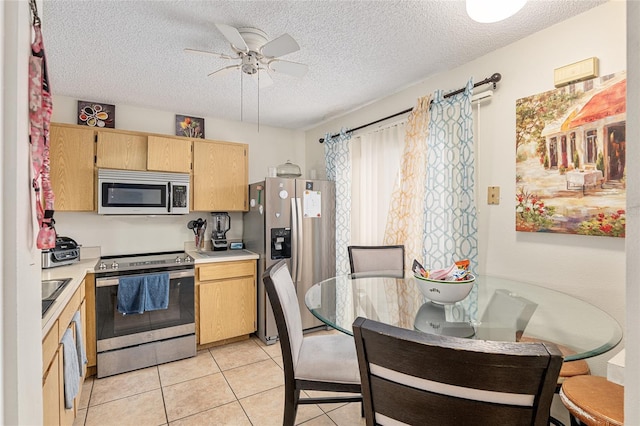 kitchen with appliances with stainless steel finishes, a textured ceiling, light tile patterned floors, and ceiling fan