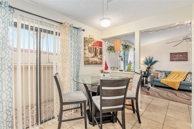 tiled dining space with ceiling fan and a textured ceiling