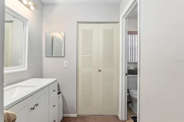 bathroom with vanity, toilet, and a textured ceiling