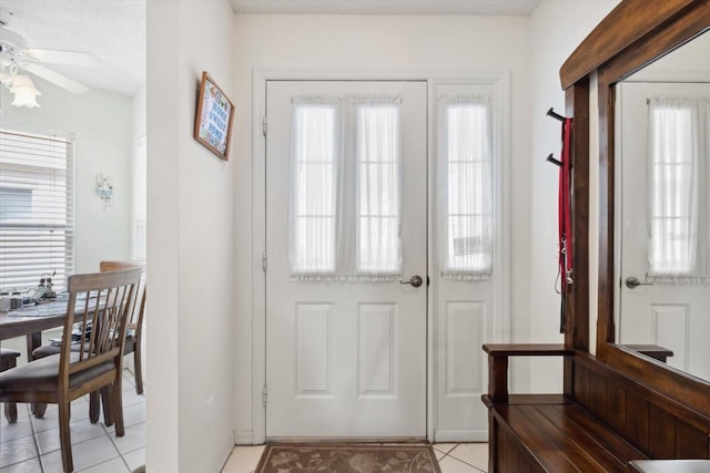 entryway featuring light tile patterned floors, a textured ceiling, and ceiling fan