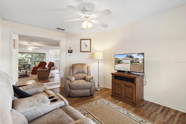 living room with ceiling fan, dark hardwood / wood-style flooring, and a textured ceiling