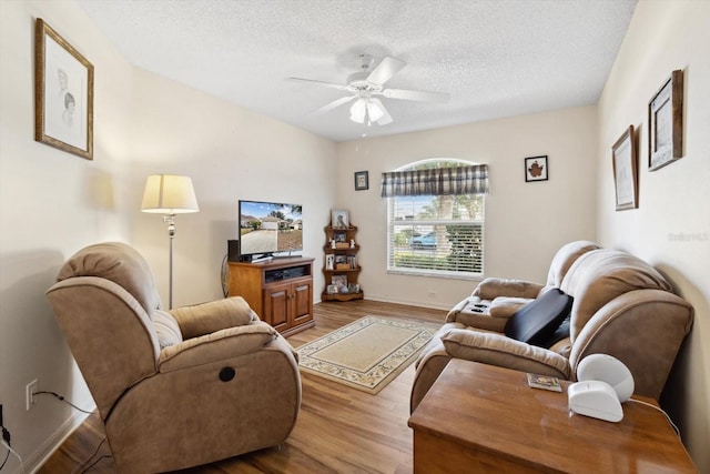 living room with ceiling fan, a textured ceiling, and hardwood / wood-style flooring