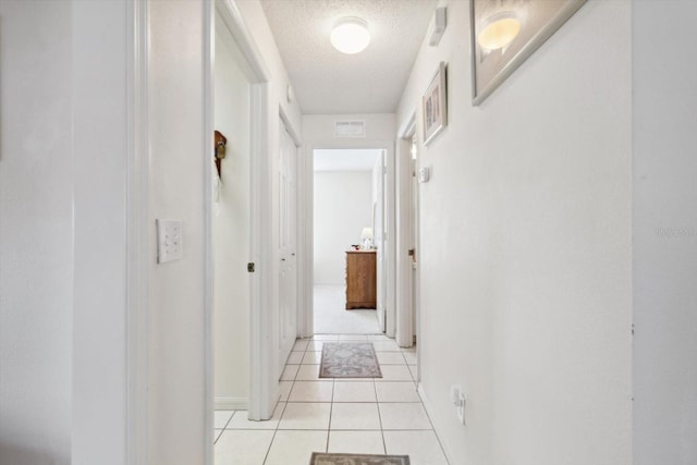 hall featuring light tile patterned floors and a textured ceiling