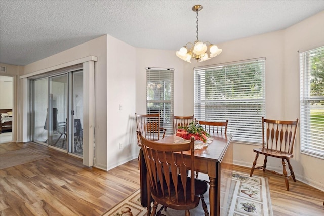 dining area with a textured ceiling, light hardwood / wood-style flooring, and a notable chandelier