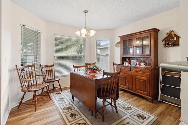 dining space featuring light wood-type flooring, a textured ceiling, and a chandelier