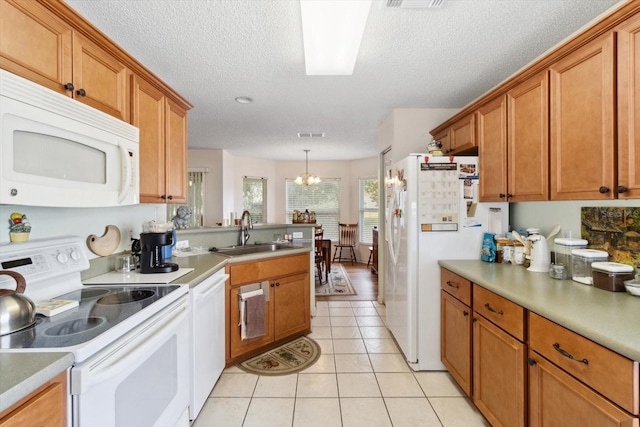 kitchen featuring a textured ceiling, white appliances, sink, a notable chandelier, and hanging light fixtures