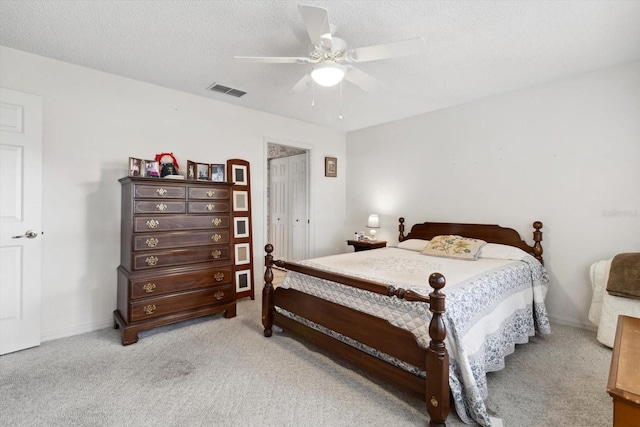 bedroom with a closet, a textured ceiling, light colored carpet, and ceiling fan