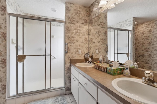 bathroom with tile patterned floors, vanity, a shower with shower door, and a textured ceiling