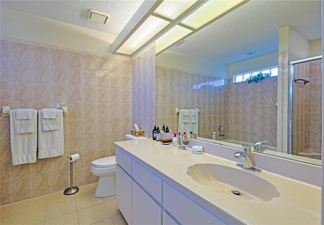 bathroom with a textured ceiling, tile patterned flooring, tile walls, and toilet