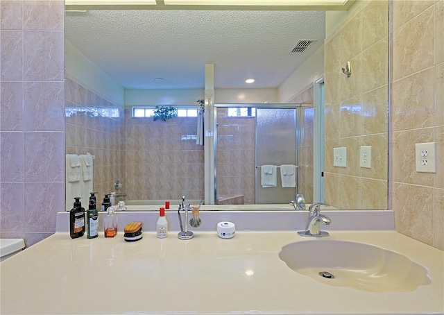 bathroom featuring tile walls, vanity, a textured ceiling, and walk in shower