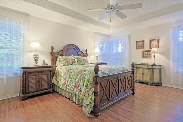 bedroom with ceiling fan, light hardwood / wood-style floors, and a textured ceiling