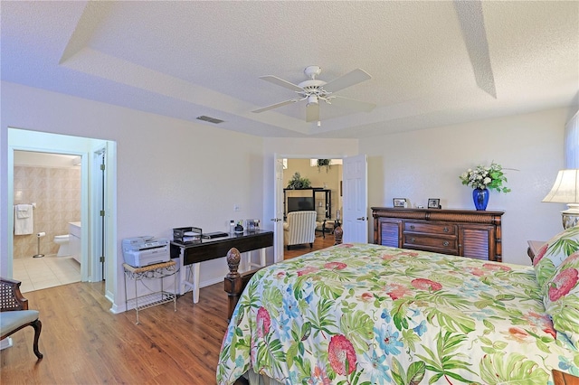 bedroom featuring wood-type flooring, a textured ceiling, ceiling fan, and connected bathroom