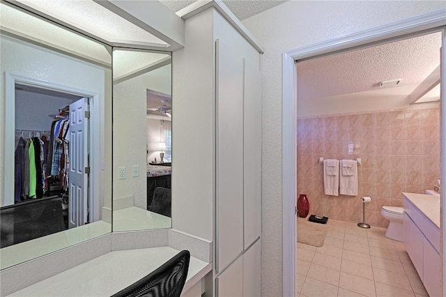 bathroom featuring tile patterned flooring, vanity, tile walls, and a textured ceiling