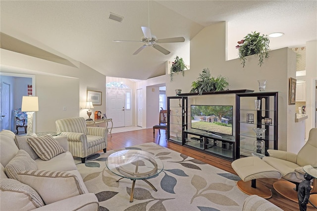 living room featuring ceiling fan, light hardwood / wood-style floors, a textured ceiling, and high vaulted ceiling