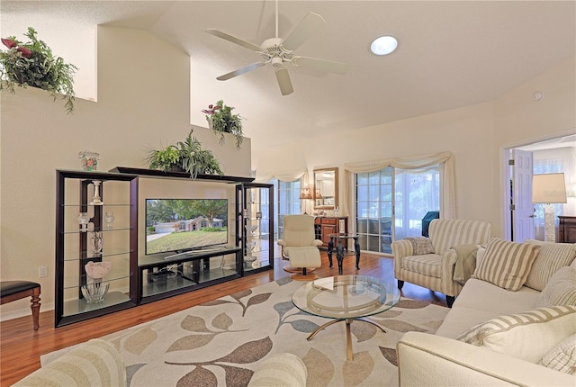 living room featuring ceiling fan, vaulted ceiling, and light wood-type flooring