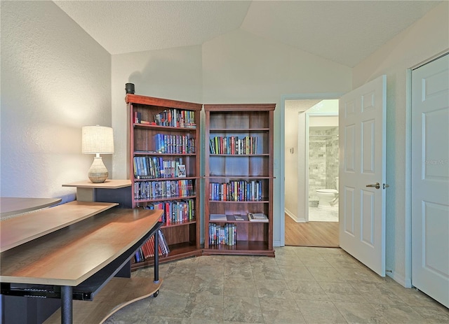 office with a textured ceiling, light wood-type flooring, and vaulted ceiling