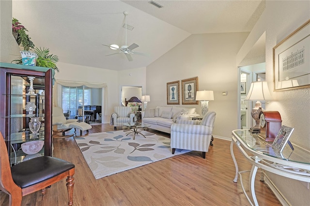 living room with ceiling fan, wood-type flooring, and lofted ceiling