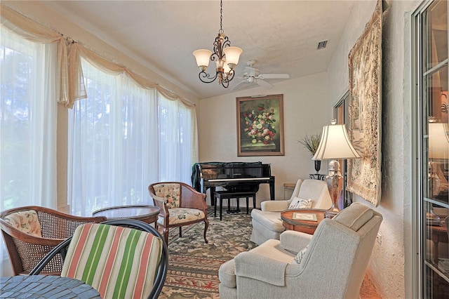 sitting room with ceiling fan with notable chandelier and lofted ceiling