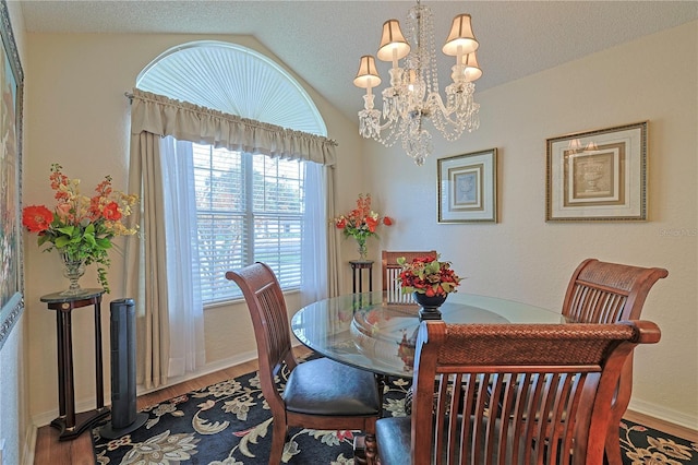 dining room with a textured ceiling, hardwood / wood-style flooring, lofted ceiling, and a notable chandelier