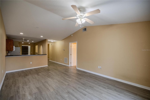 unfurnished living room featuring vaulted ceiling, light hardwood / wood-style flooring, and ceiling fan