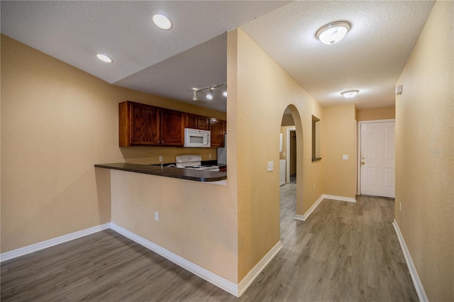 kitchen featuring a textured ceiling, kitchen peninsula, light hardwood / wood-style flooring, and white appliances