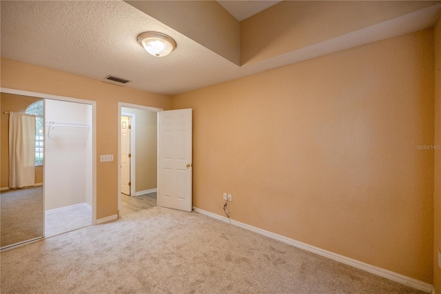 unfurnished bedroom with light carpet, a textured ceiling, and a closet