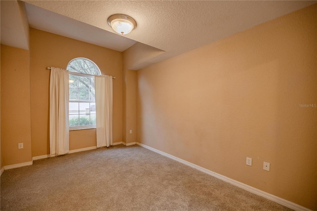 carpeted empty room featuring a textured ceiling