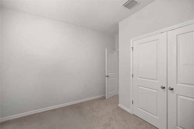 unfurnished bedroom featuring light carpet and a closet