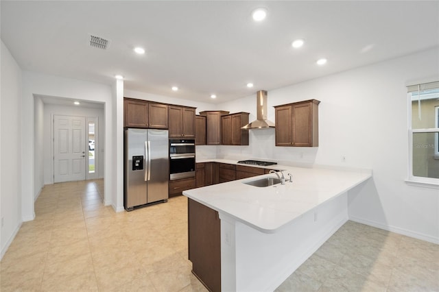 kitchen with kitchen peninsula, stainless steel appliances, wall chimney exhaust hood, and sink