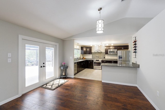 kitchen with french doors, wall chimney exhaust hood, backsplash, kitchen peninsula, and appliances with stainless steel finishes