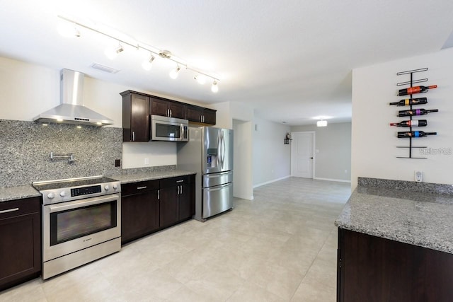 kitchen with dark brown cabinets, light stone countertops, wall chimney range hood, and appliances with stainless steel finishes