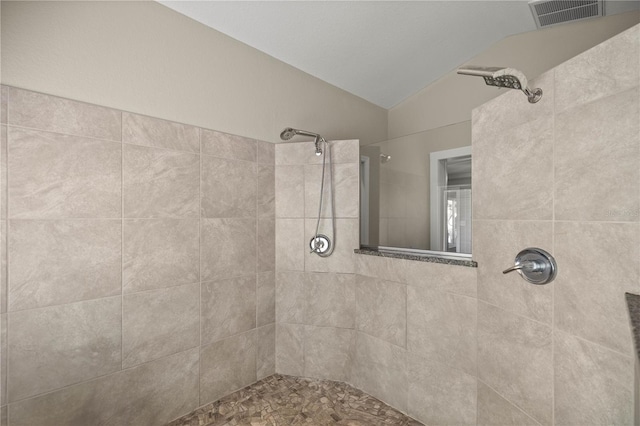 bathroom featuring a tile shower and lofted ceiling