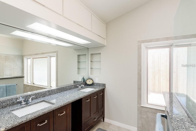 kitchen featuring light tile patterned floors, dark brown cabinetry, light stone counters, and sink