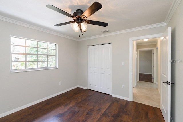 unfurnished bedroom featuring ceiling fan, dark hardwood / wood-style floors, ornamental molding, and a closet