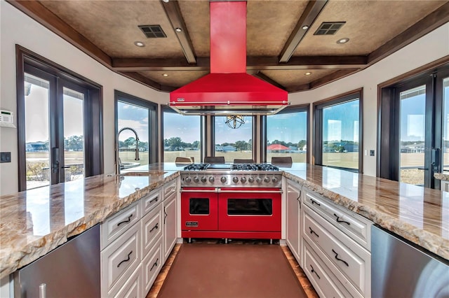 kitchen featuring light stone counters, double oven range, white cabinets, and island exhaust hood