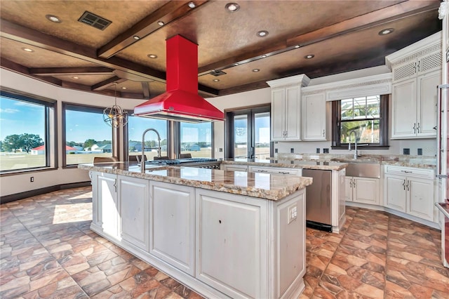 kitchen featuring beam ceiling, sink, white cabinets, and a kitchen island with sink