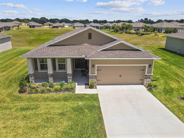 view of front of house with covered porch, a garage, and a front lawn