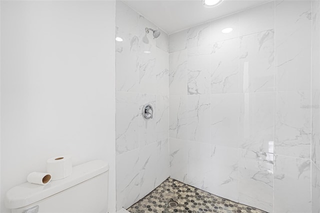 bathroom featuring a tile shower and toilet