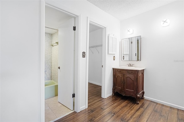 bathroom with hardwood / wood-style floors, vanity, a textured ceiling, and tiled shower / bath combo