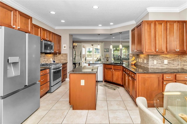 kitchen with sink, stainless steel appliances, ornamental molding, a kitchen island, and kitchen peninsula