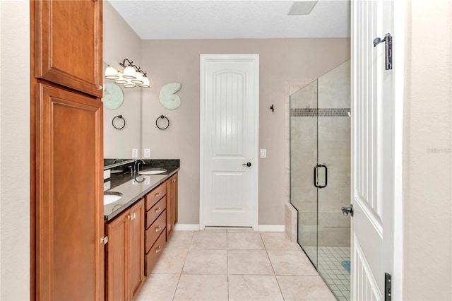 bathroom featuring tile patterned flooring, vanity, an enclosed shower, and a textured ceiling