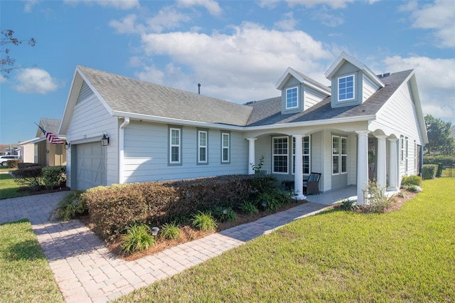 cape cod house with covered porch, a front yard, and a garage