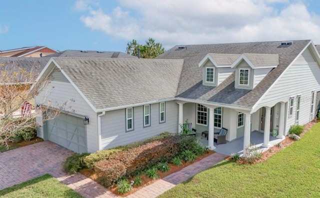 view of front of home featuring a porch, a garage, and a front lawn