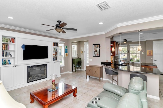 tiled living room featuring sink, crown molding, a textured ceiling, and ceiling fan