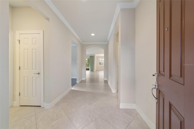 hall featuring light tile patterned floors and crown molding